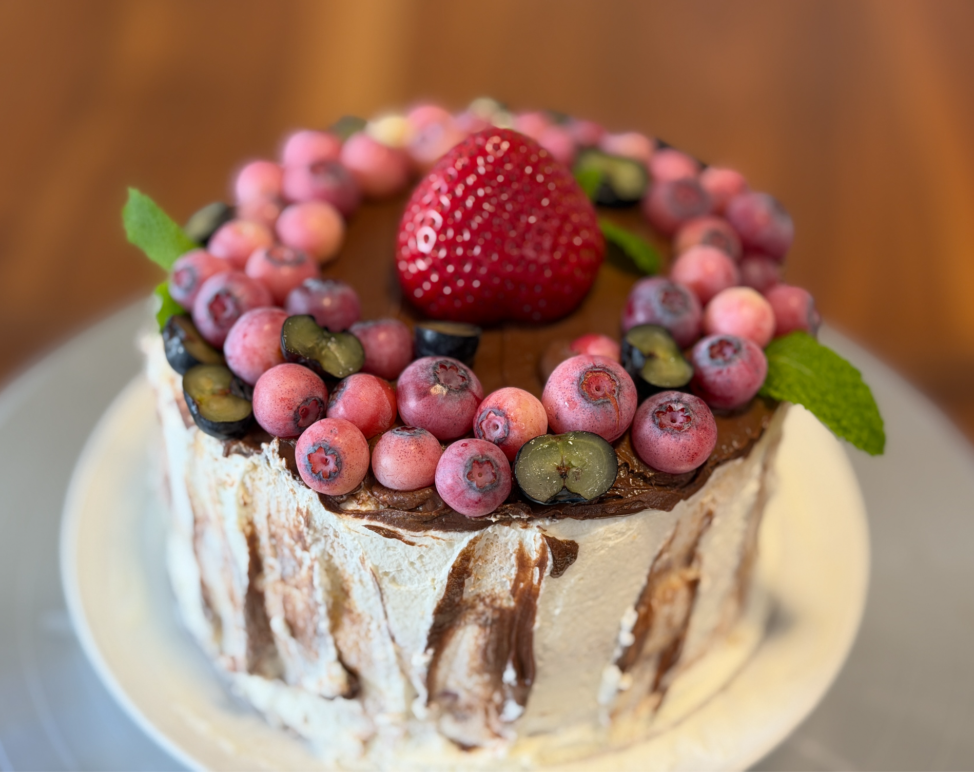 Organic birthday cake topped with fresh berries and mint